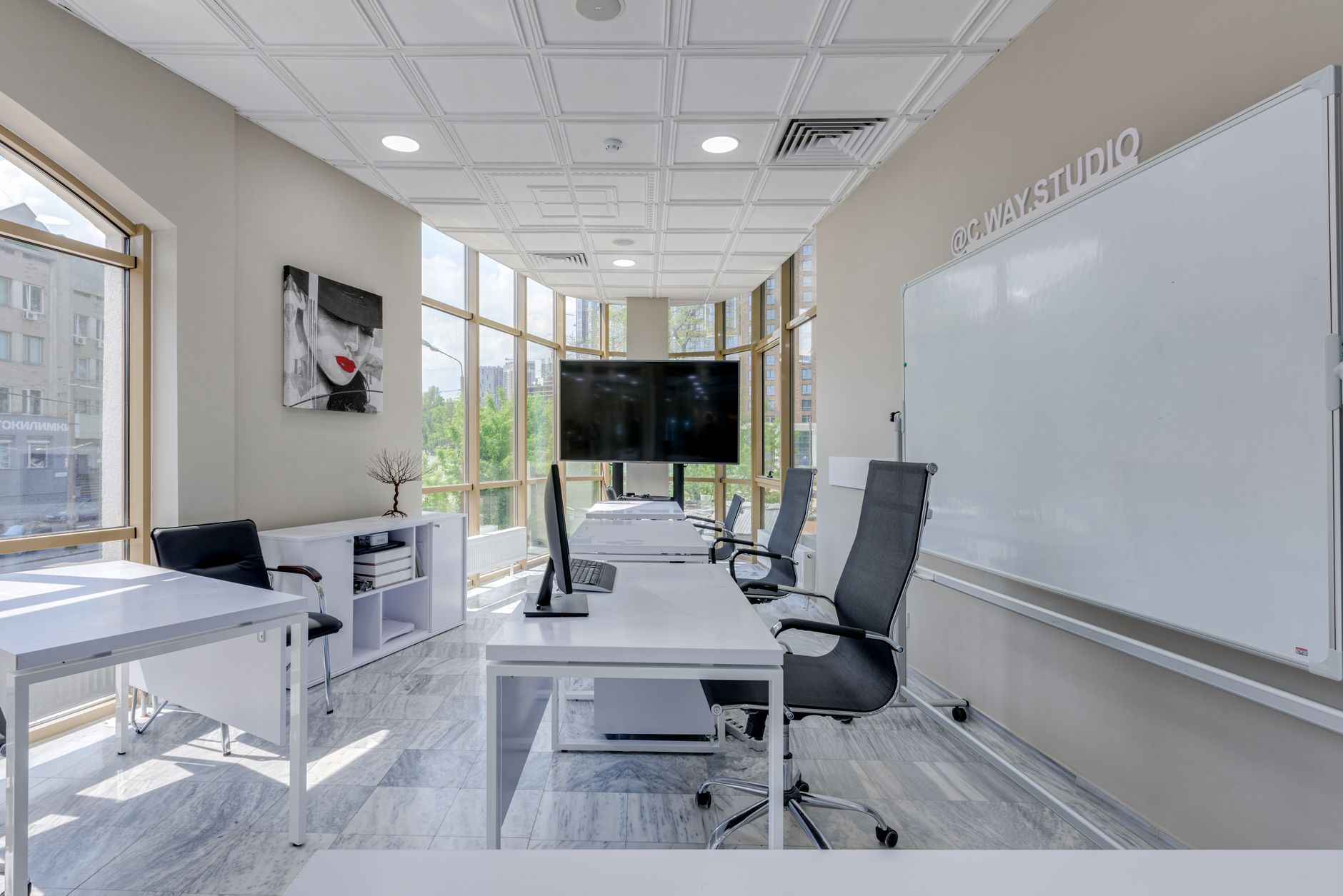 a startup accelerator workspace interior with rows of desks, monitors, and whiteboards covered in diagrams, photographed from an elevated angle showing the full open floor plan