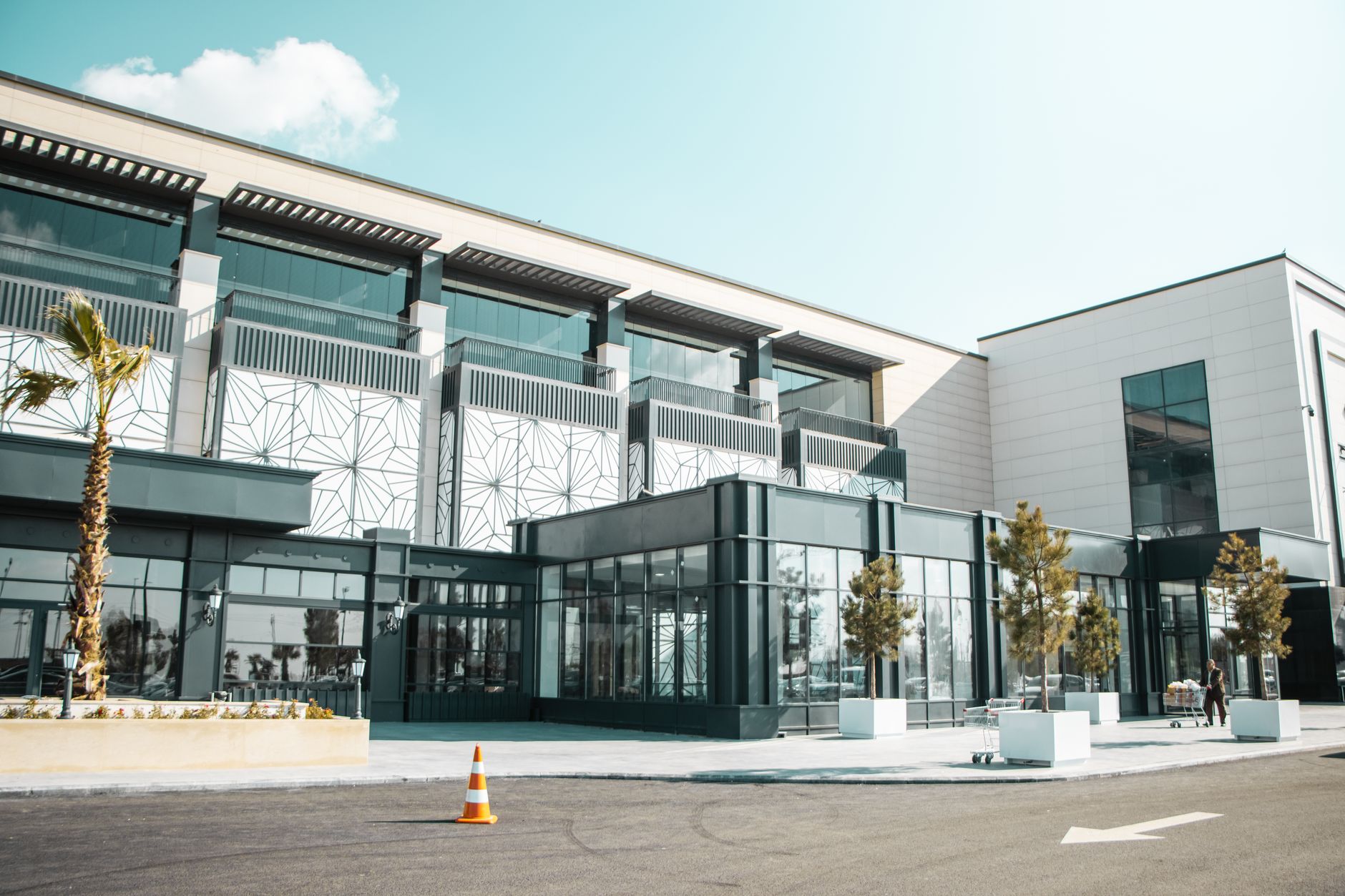 a modern glass-and-steel tech campus in Tel Aviv at midday, with palm trees lining the entrance plaza and autonomous delivery vehicles visible on the ground level