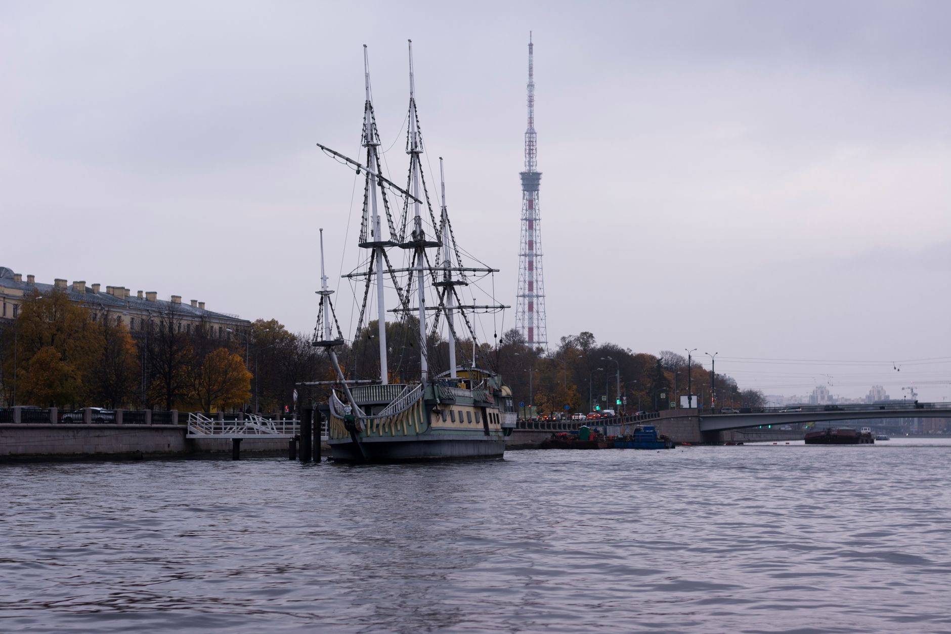 A modern Japanese naval frigate moored at a naval base, seen from the pier with gray hull and radar masts visible against an overcast sky