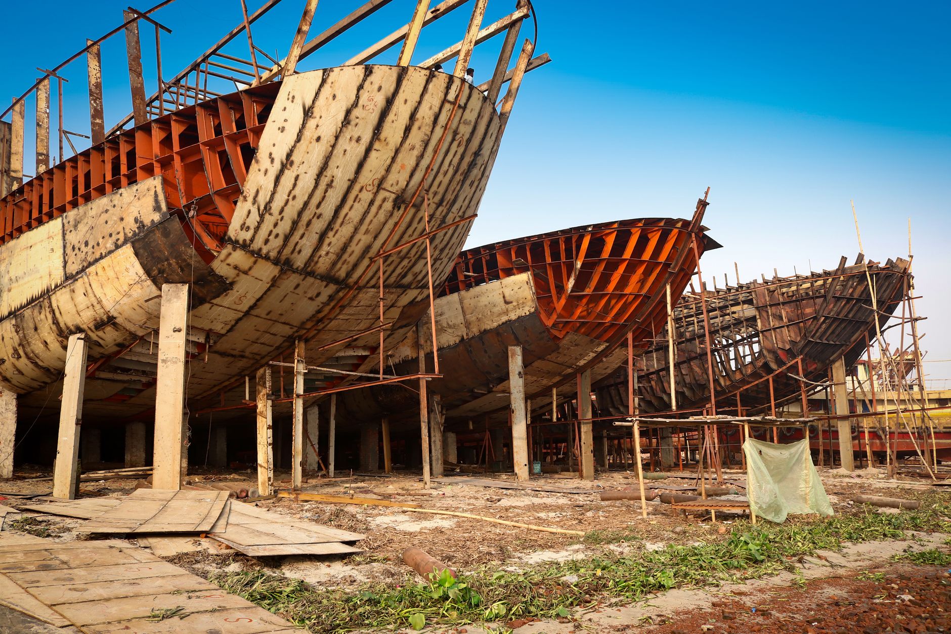 A submarine in dry dock at a Japanese shipyard, viewed from above at an angle, showing the vessel's dark hull and sail structure surrounded by scaffolding