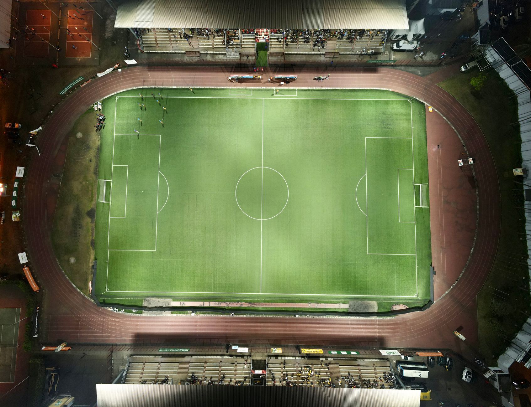 wide-angle view of an empty professional football stadium with field markings visible, natural turf under stadium lights at dusk
