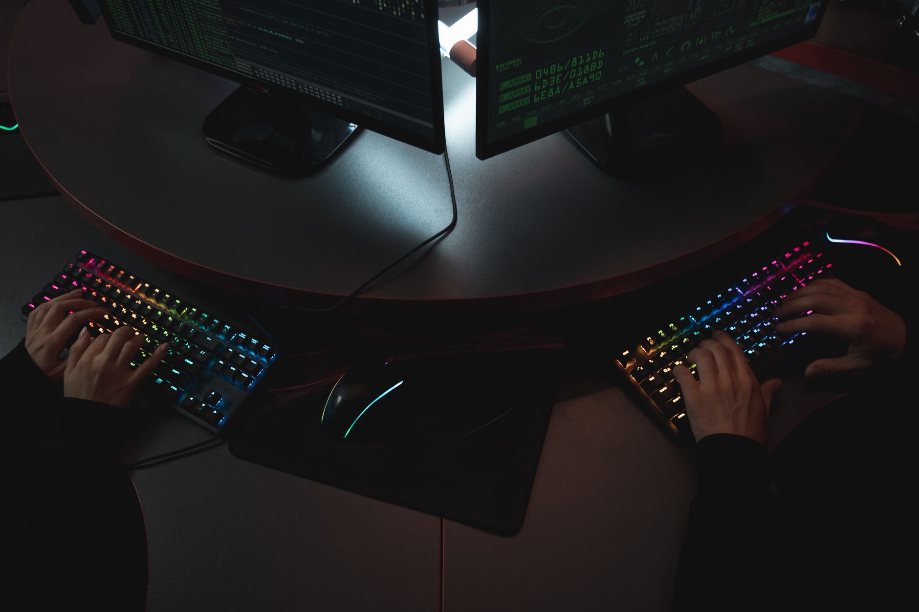 a modern open-plan cybersecurity operations center with rows of workstations displaying network monitoring dashboards, viewed from an elevated angle