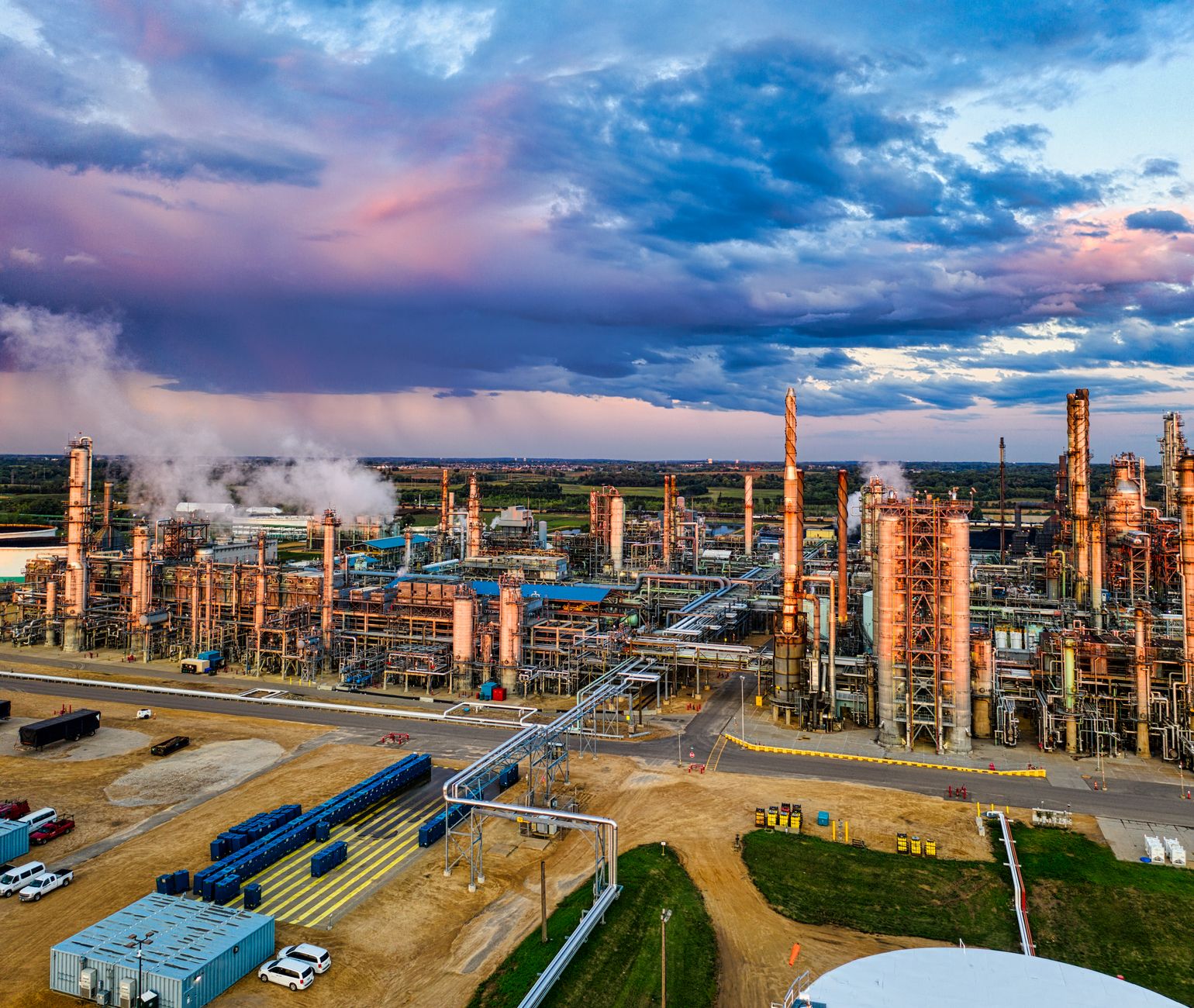 an aerial view of a European industrial complex with multiple separate production buildings spread across a large campus, surrounded by rail links and warehousing structures