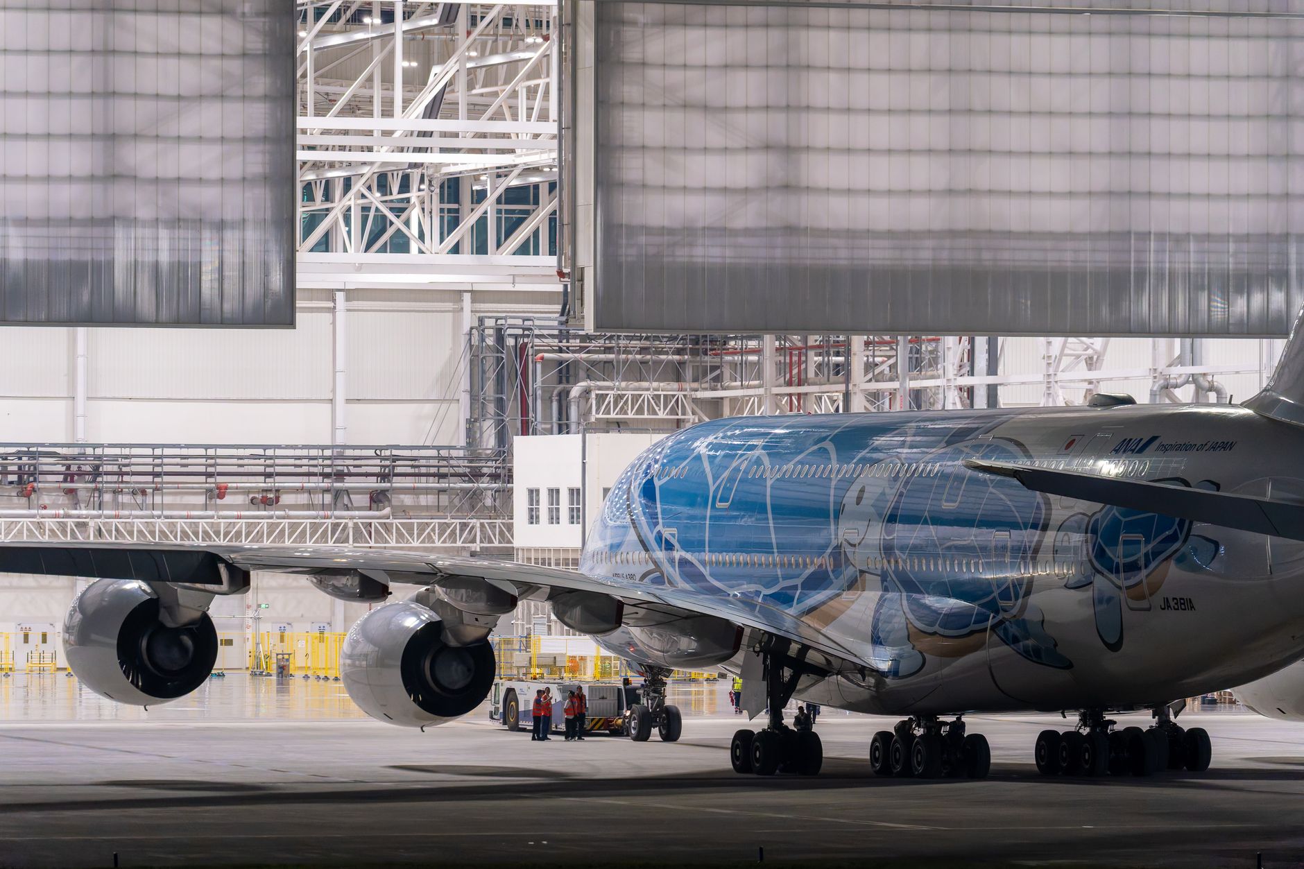 an F-35C Lightning II on a carrier elevator platform being lowered into a hangar bay, with maintenance crew equipment visible in the background