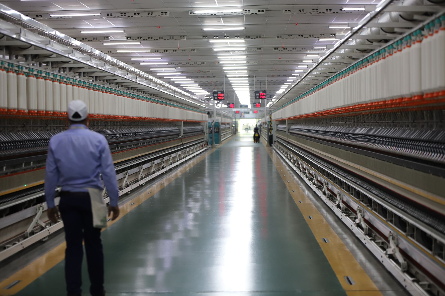 a large defense manufacturing facility interior showing long assembly lines with missile or munitions casings in various stages of production, fluorescent lighting overhead, no people as focal point