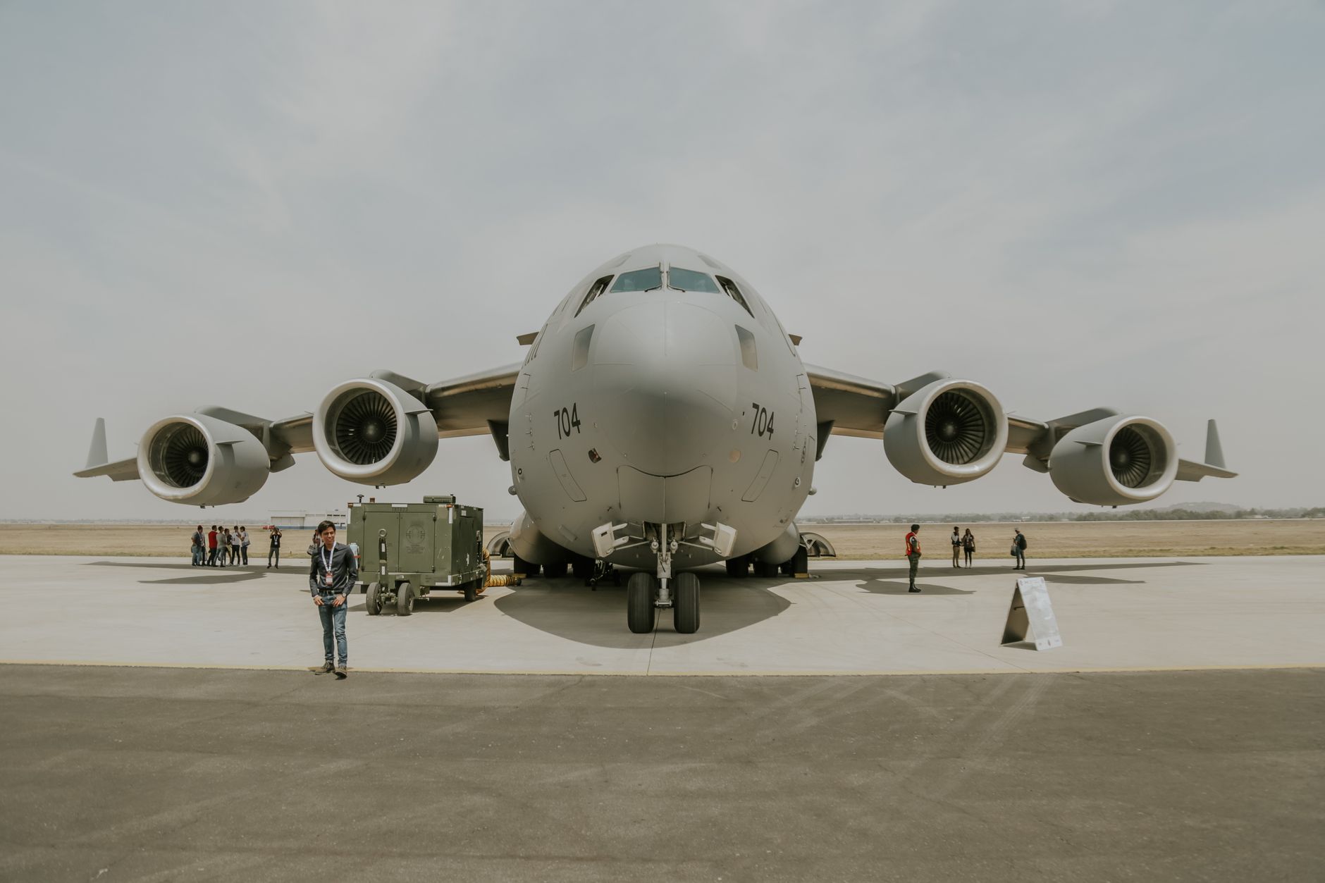 a drone-in-a-box autonomous launch unit deployed on an open tarmac at an outdoor security installation, surrounded by perimeter fencing, no people as focal point