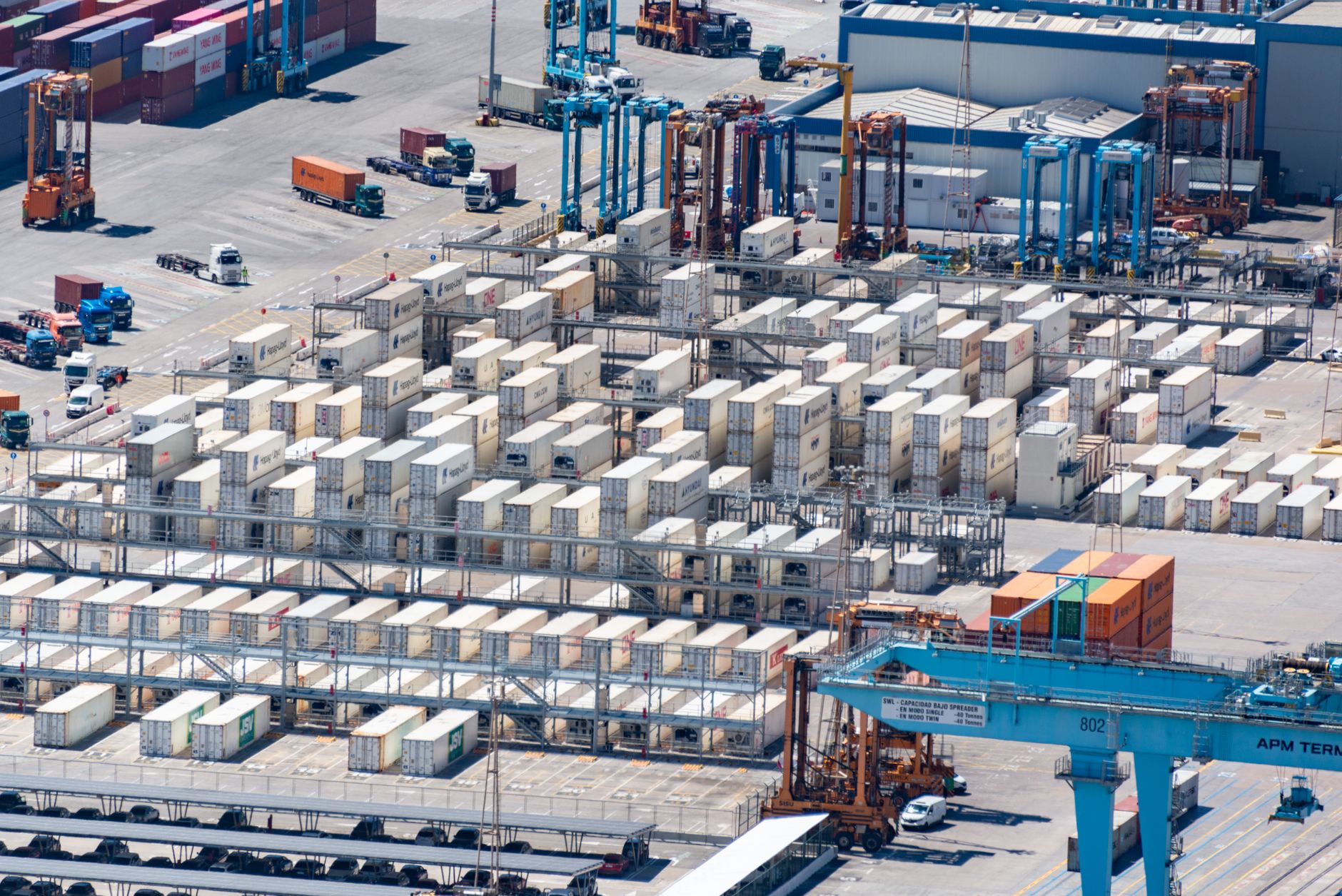 rows of armored personnel carriers parked inside a large covered NATO logistics depot, maintenance equipment and overhead lighting visible, facility infrastructure as the focal point