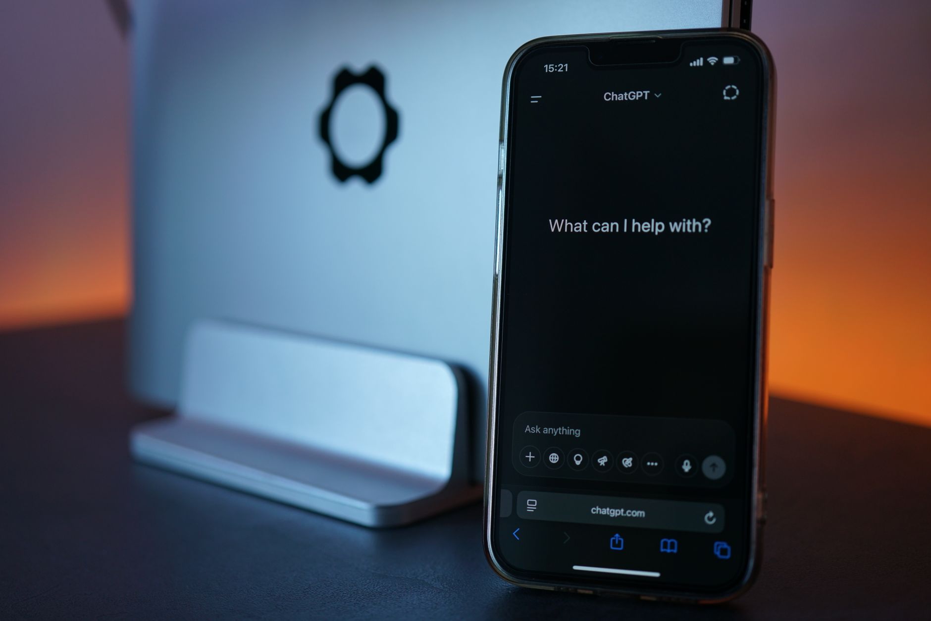 a close-up of a smartphone resting on a desk displaying a voice-interaction language learning interface, with audio waveform visualization on screen and soft ambient office lighting in the background