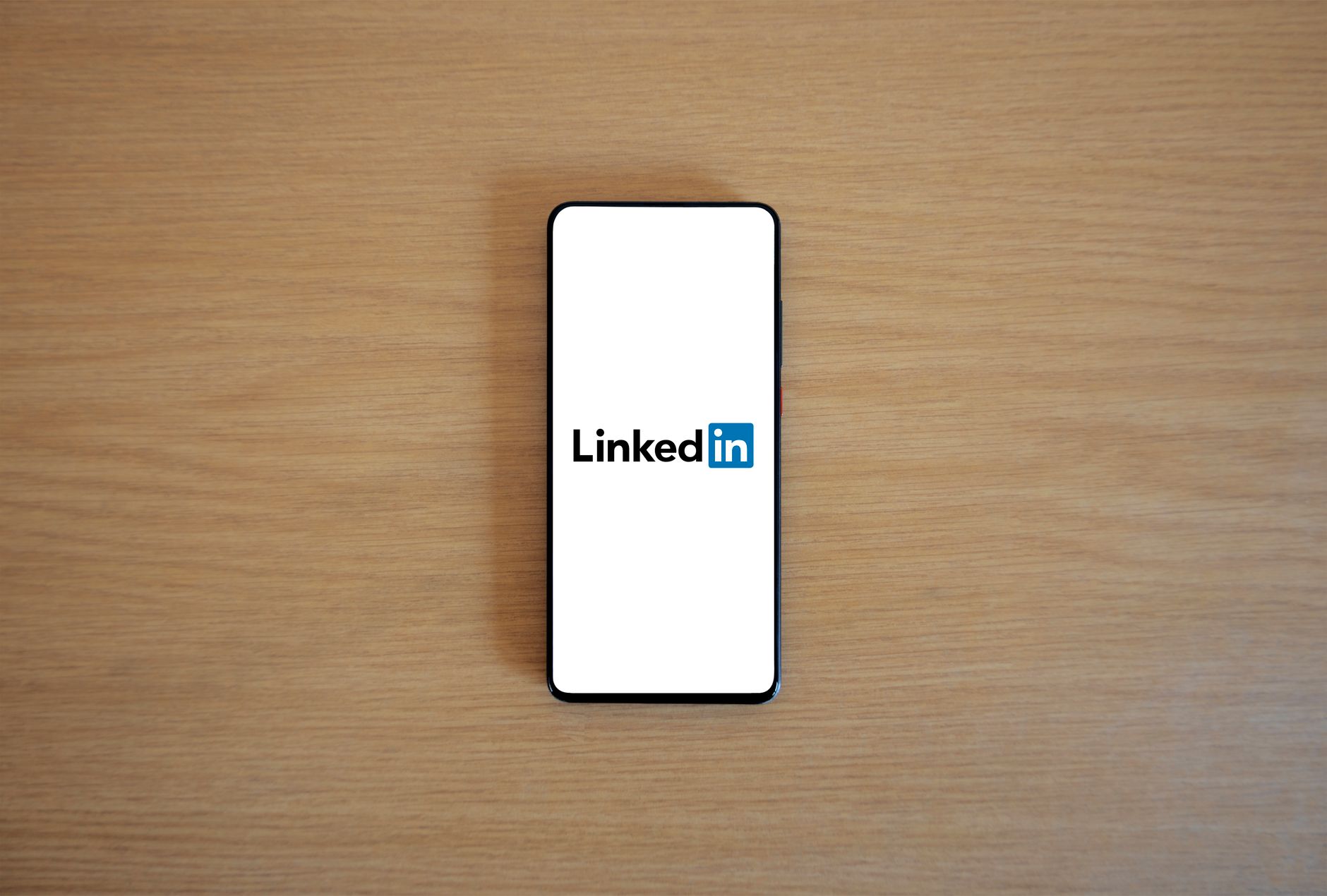 a weathered copy of Ms. Magazine resting on a wooden table beside a modern smartphone displaying a social media feed, shot from above in natural light