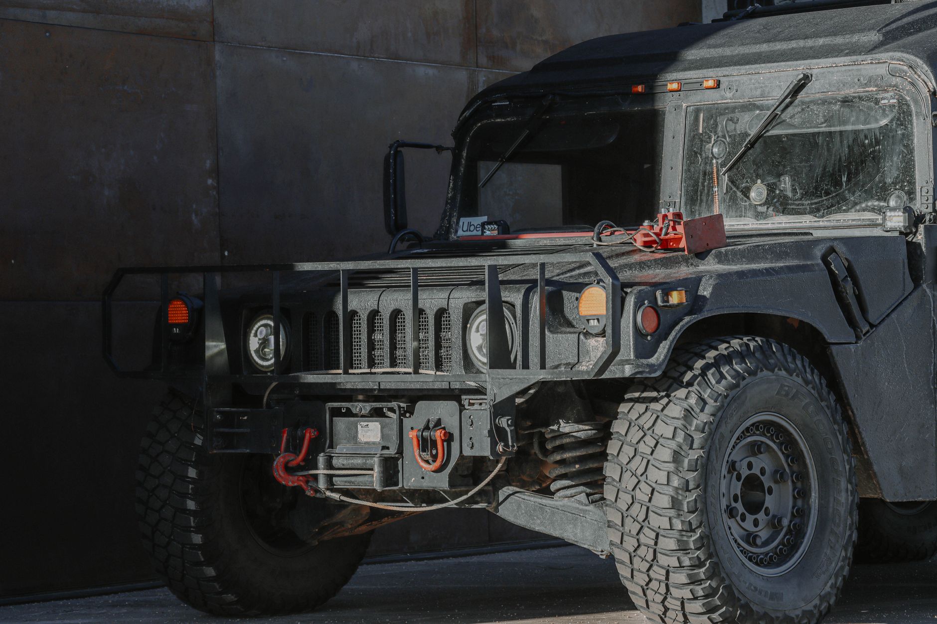a wheeled 8x8 armored vehicle with a large-caliber gun turret parked on a paved test range, surrounded by low hills and open sky
