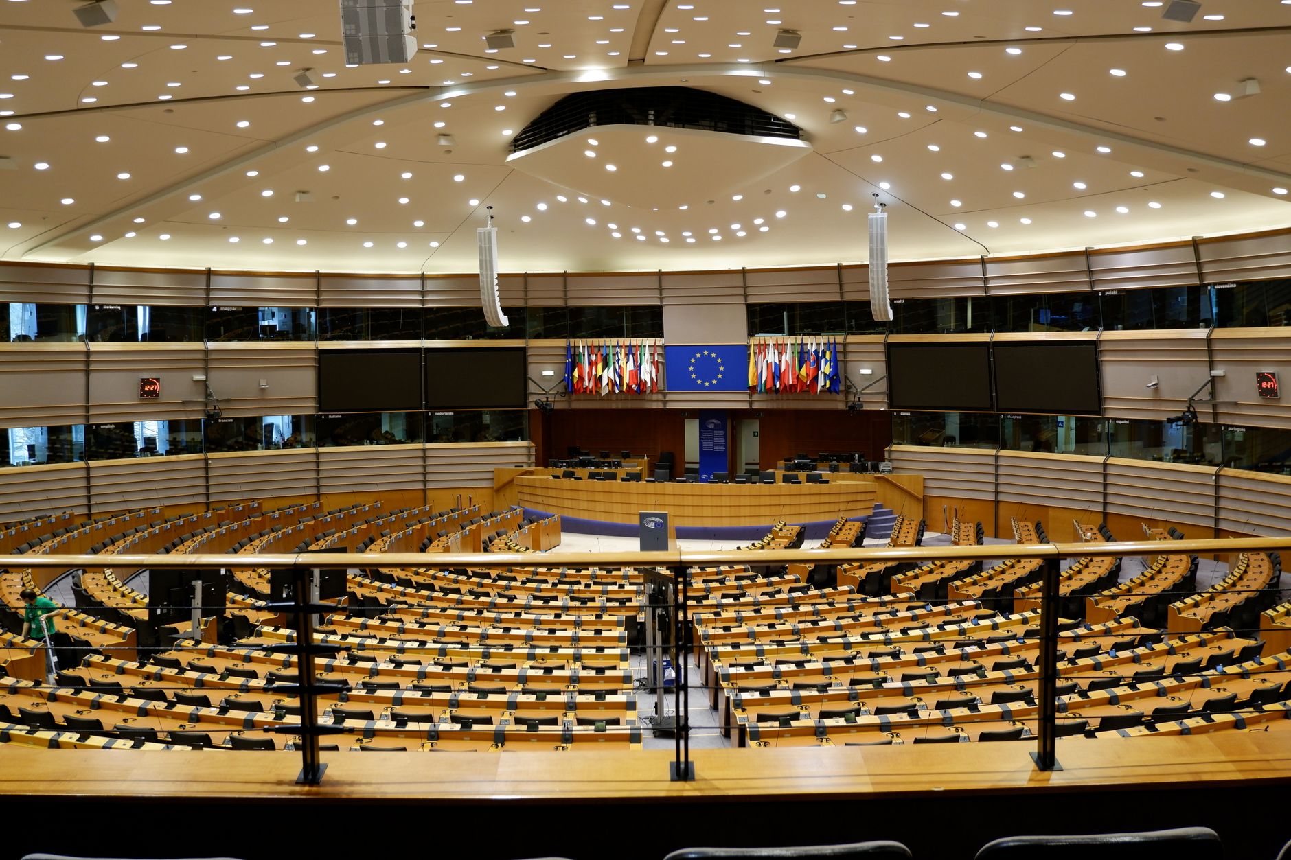 wide-angle exterior shot of the European Union Council building in Brussels, flags lining the facade on a overcast day, no people in foreground