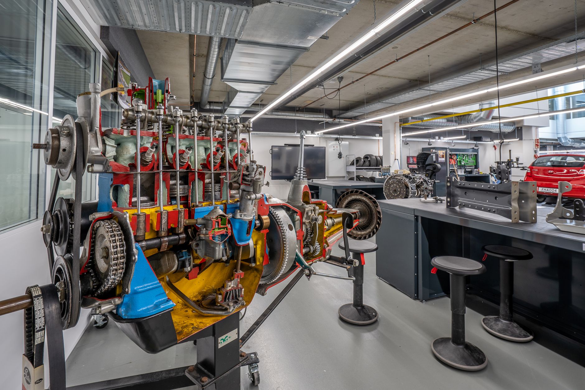 interior of a university-style engineering laboratory with satellite mockups and orbital mechanics displays mounted along the walls, workstations arranged in rows