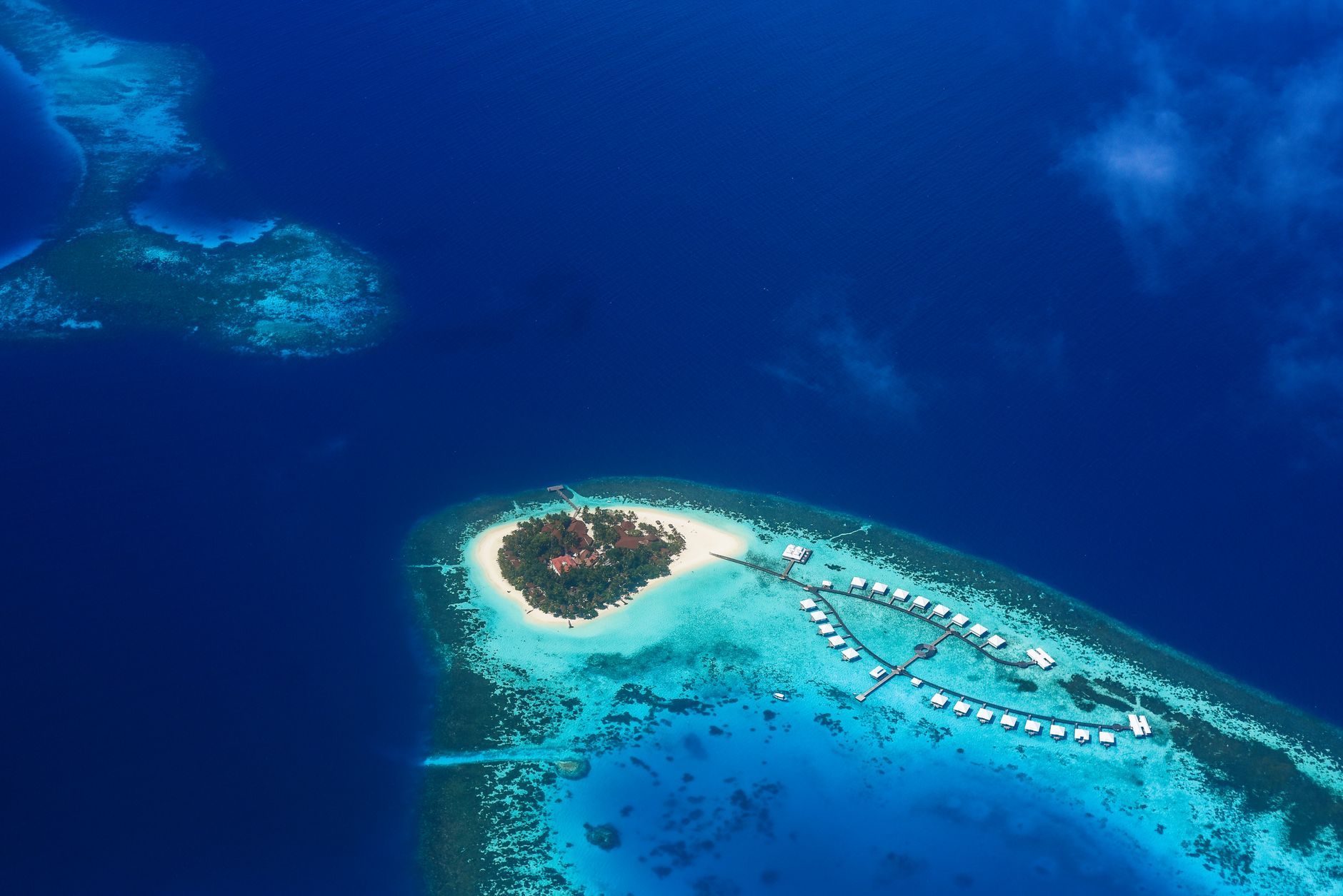 aerial view of a remote tropical island airbase with long runways and parked heavy aircraft visible from altitude, surrounded by turquoise ocean