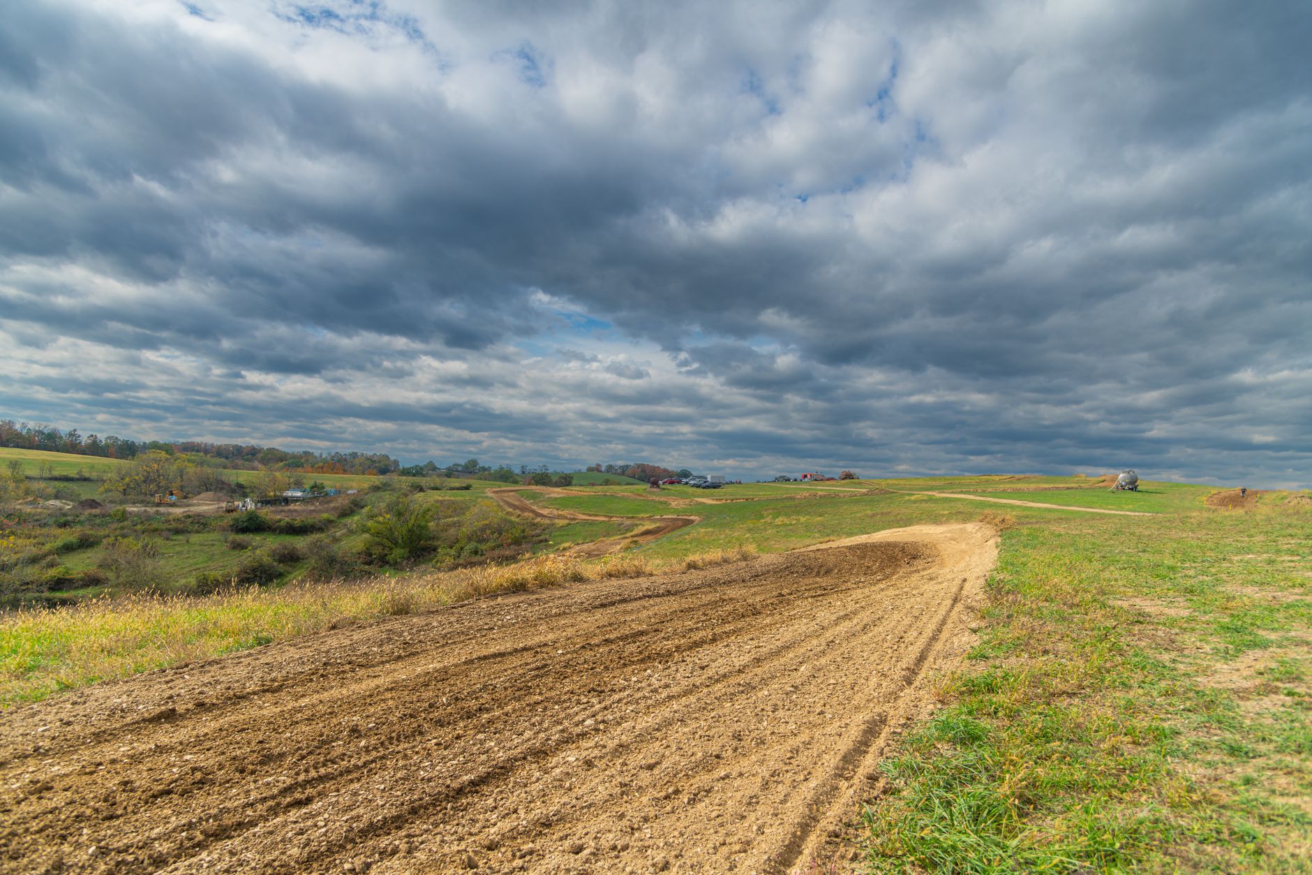 a small tracked ground robot on a dirt field during a technical evaluation, with open terrain and treeline visible in the background