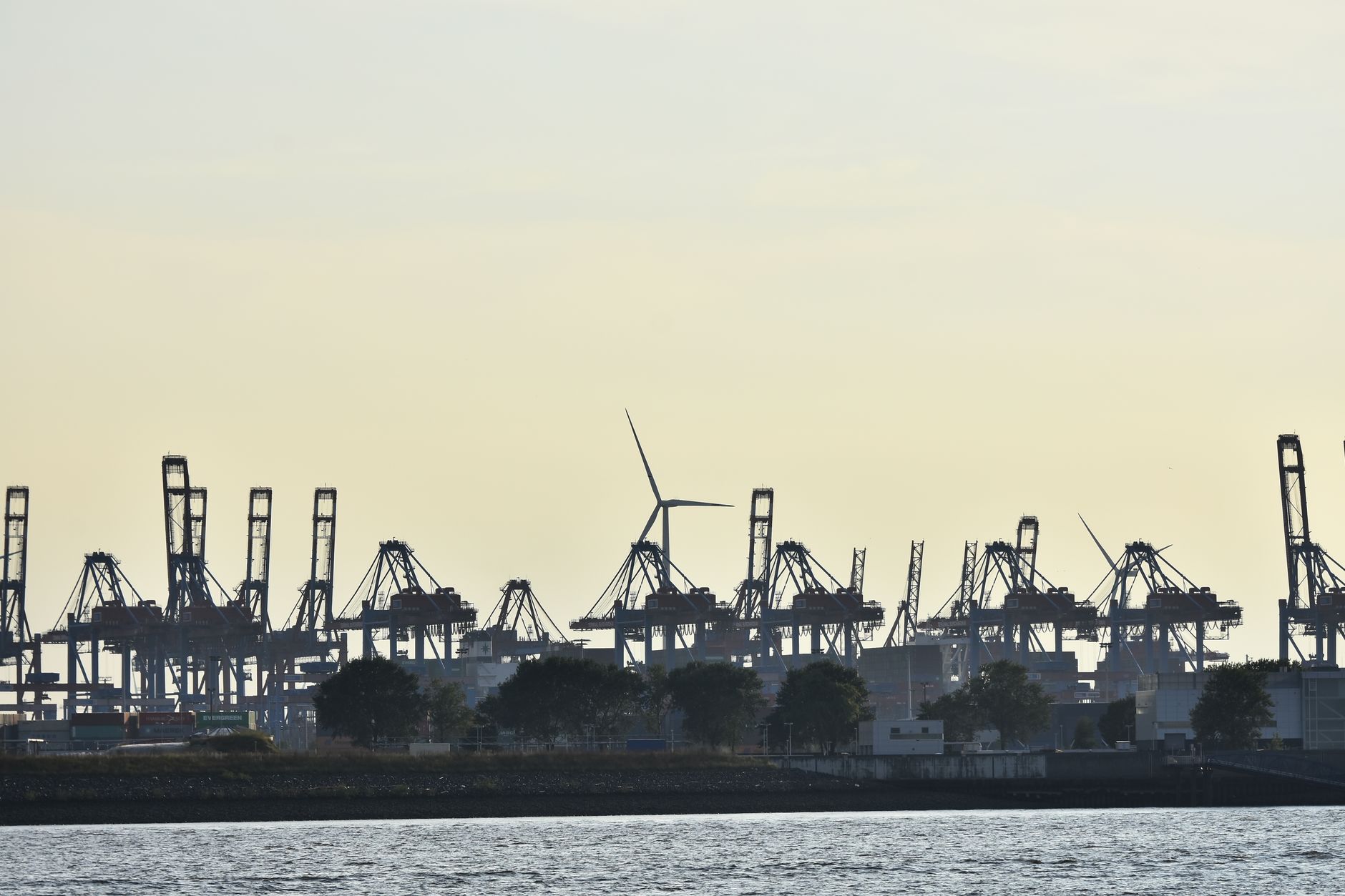 a coastal harbor district at dusk with civilian port infrastructure and industrial buildings visible along the waterfront, no people in the foreground