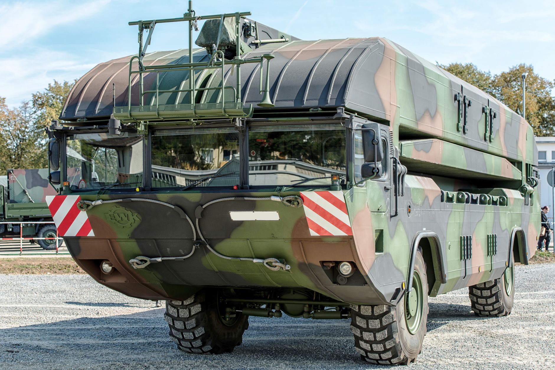 a mobile ground-based air defense launcher mounted on a military truck chassis, parked on open terrain with missile rails visible, no people in foreground