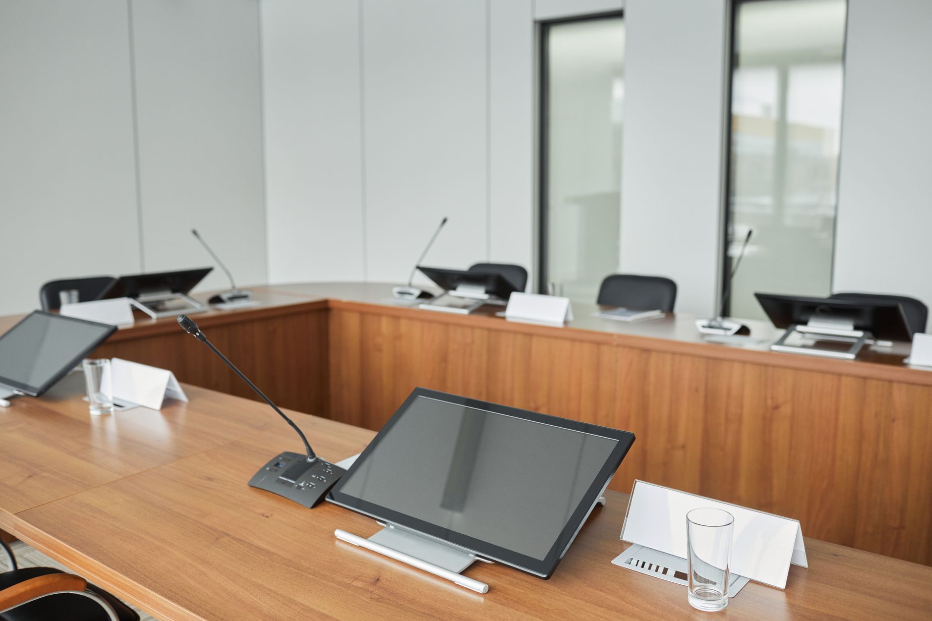 a wide-angle shot of a diplomatic conference room with a long table, national flags in the background, and communications equipment visible on a side console