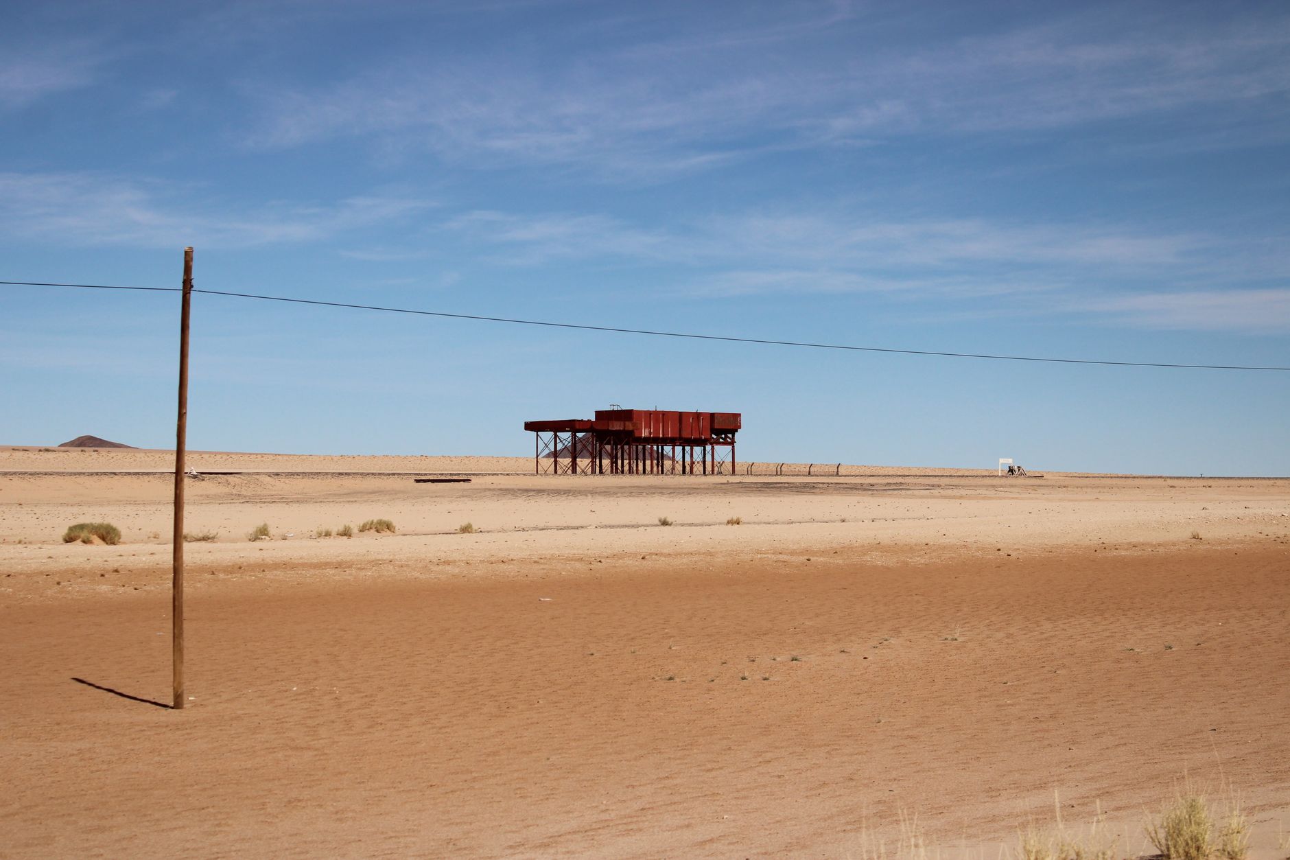 a wide-angle view of a hardened military air base facility in an arid desert environment, aircraft shelters visible in the background, no personnel in foreground