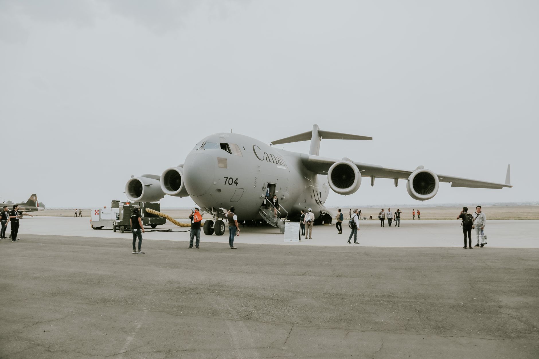 a C-130H aircraft on the tarmac of an air reserve station, spray modification equipment visible beneath the wings, ground crew equipment staged nearby