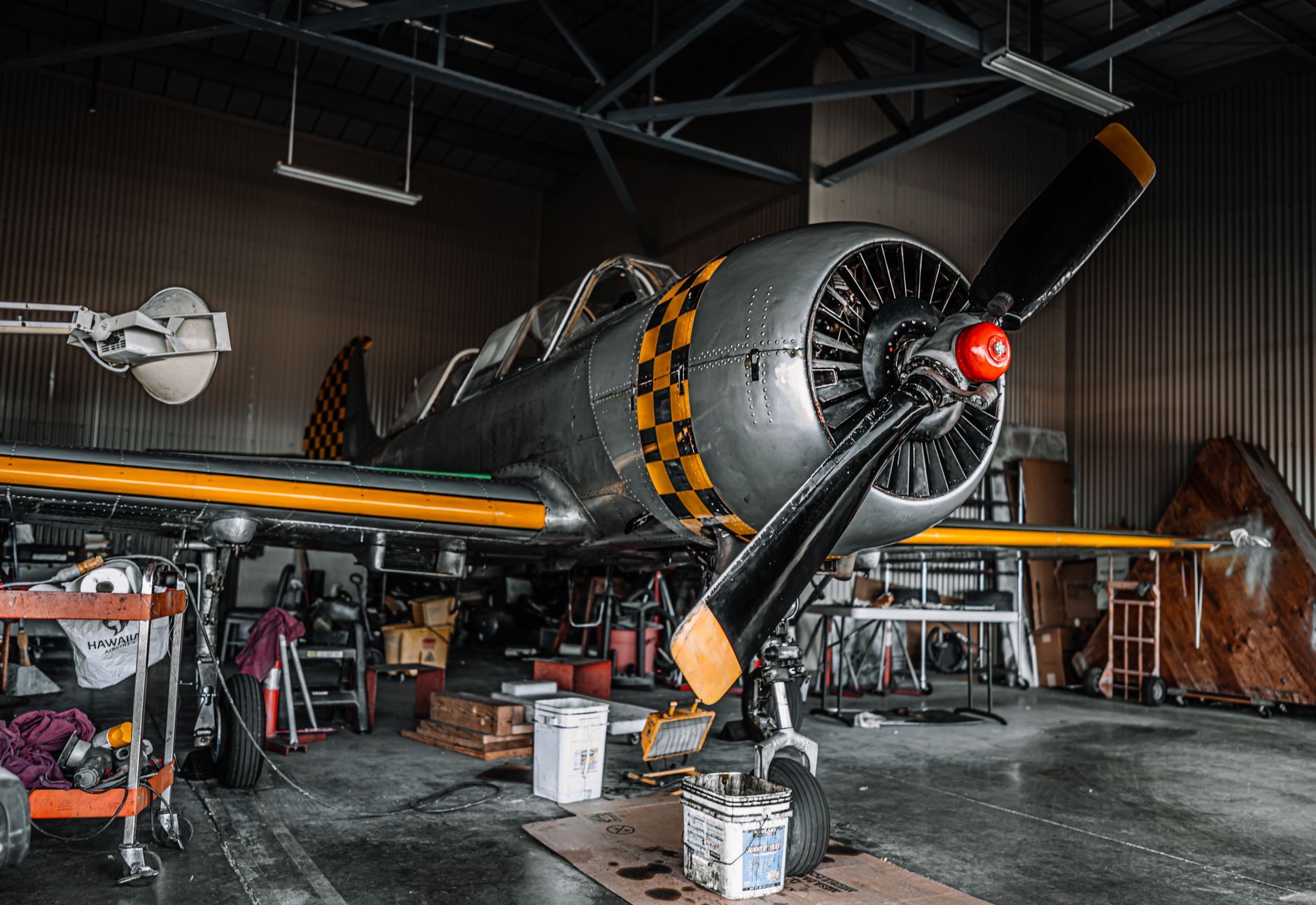 interior view of a military aircraft hangar at an air reserve station, an aging C-130 airframe undergoing maintenance with scaffolding and equipment surrounding it