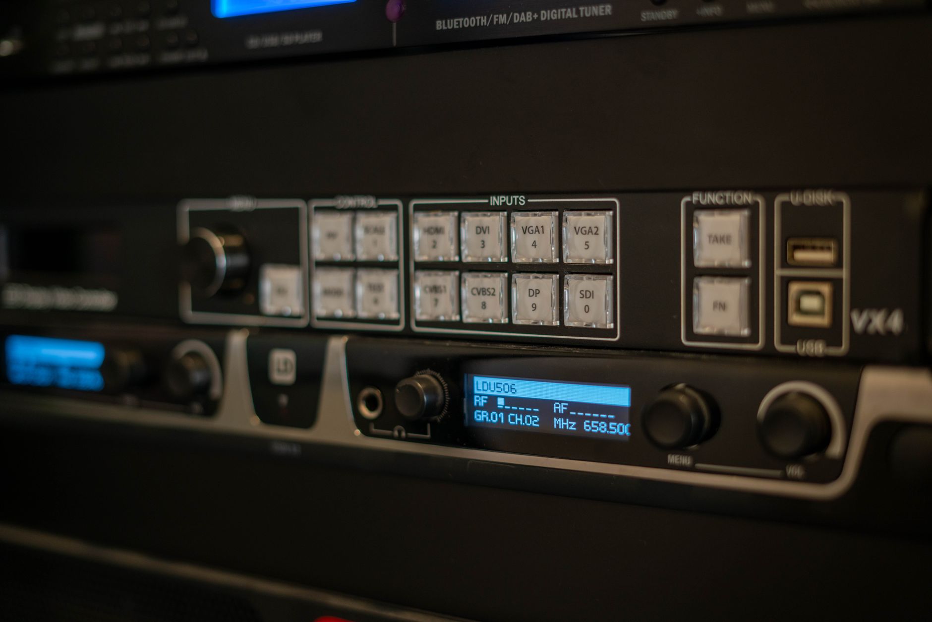 a rack of compact drone control units and tethered headset interfaces arranged on a testing bench inside a hardware development laboratory