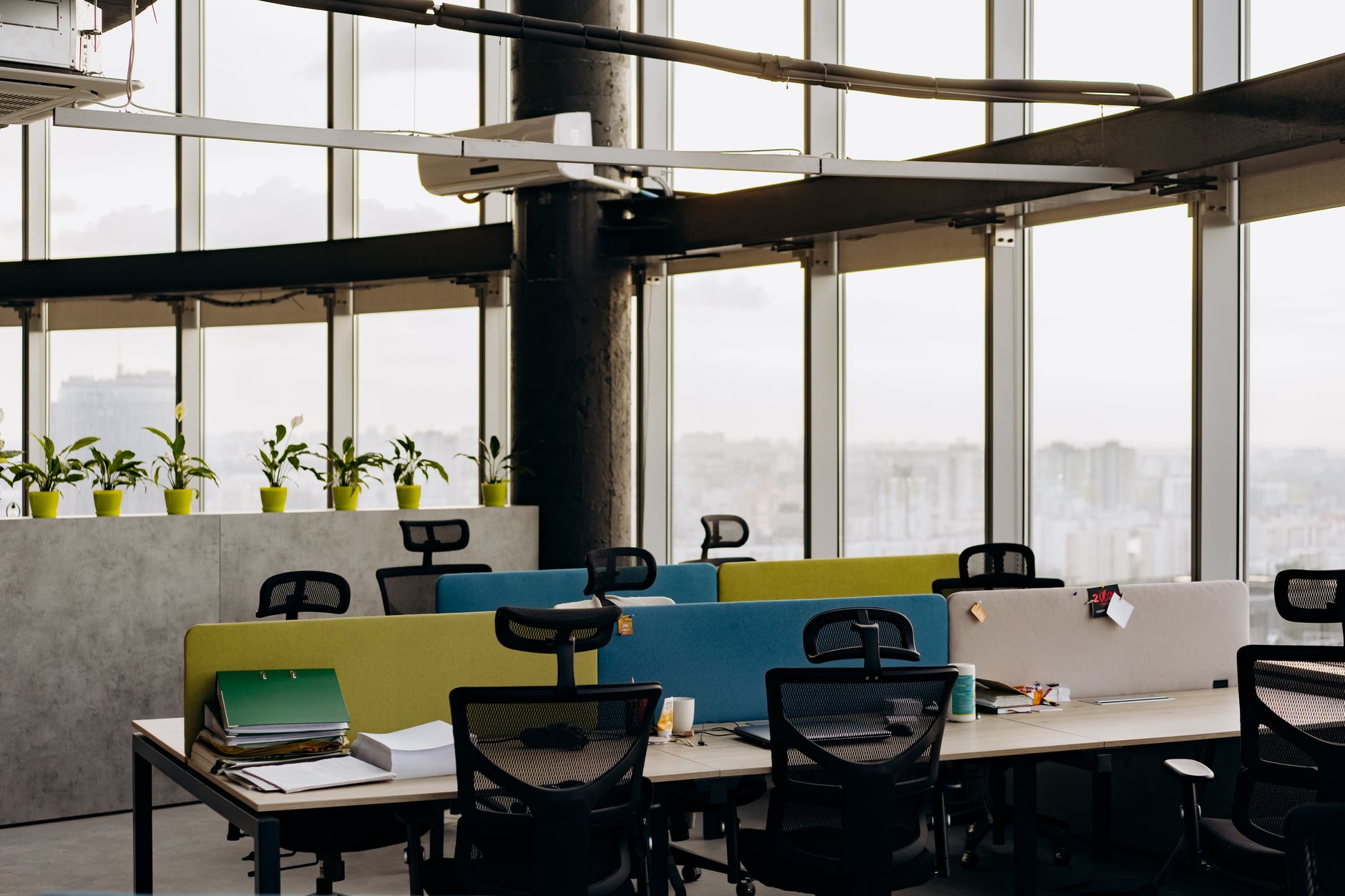 an open-plan technology office workspace with workstations and whiteboards, viewed from a wide angle showing the environment rather than individuals
