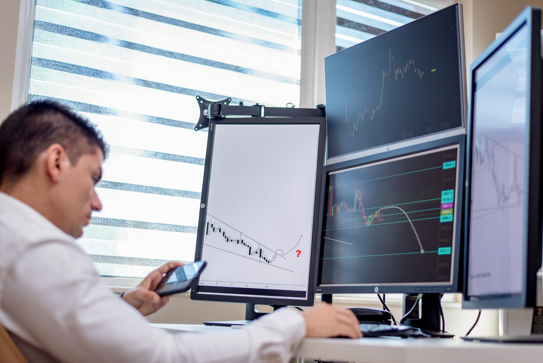 a modern open-plan financial technology office with rows of monitors displaying trading data charts and network diagrams, interior daytime lighting