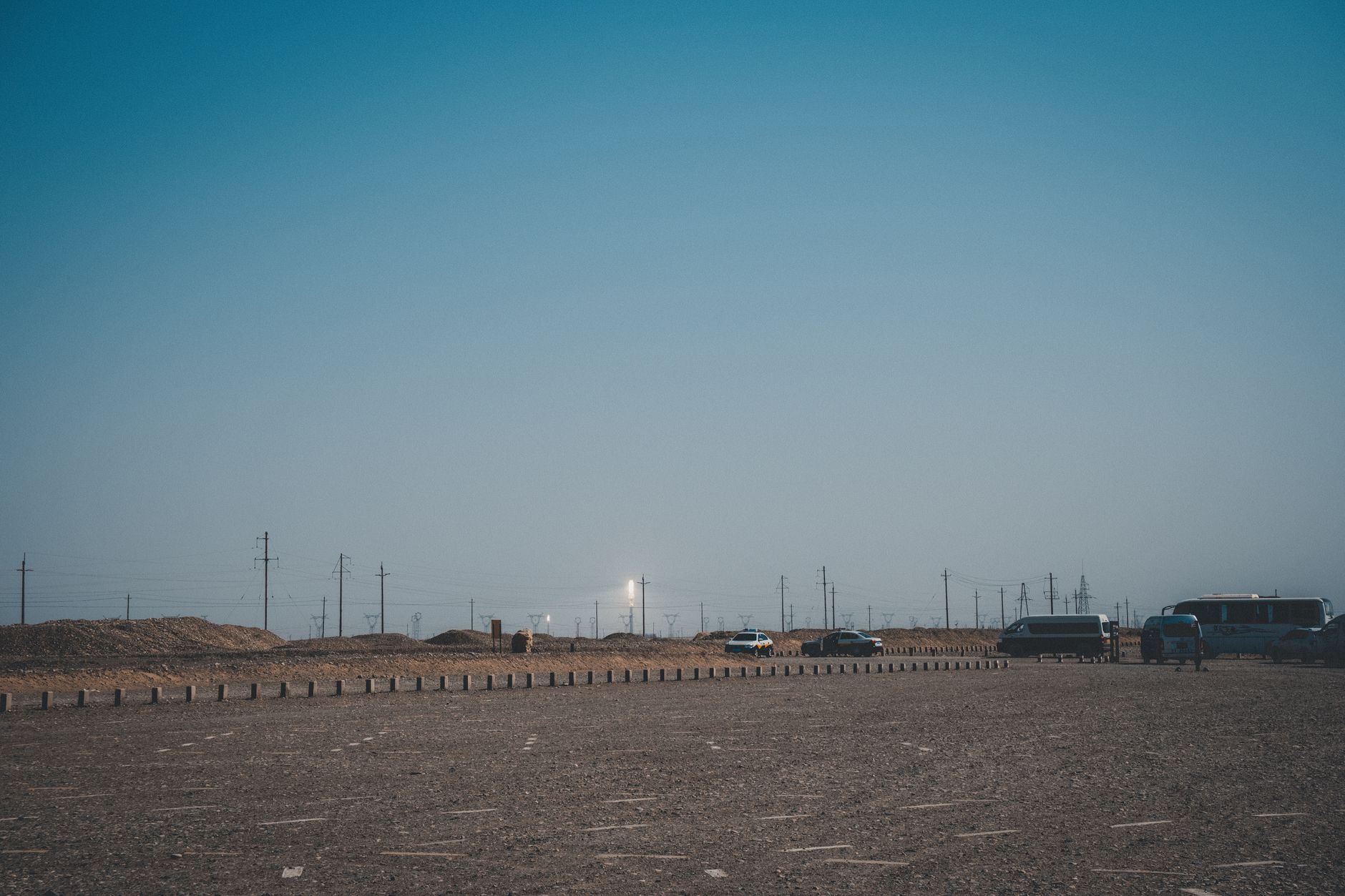 a Saudi-coalition military logistics base with armored vehicles parked in formation on a desert hardstand, viewed from a distance