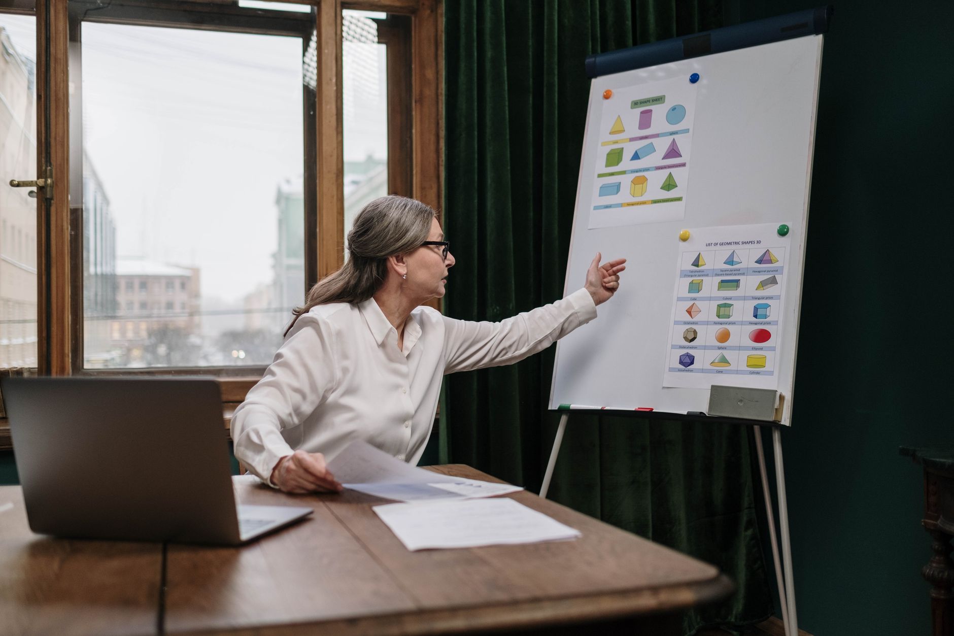 a conference room inside a venture capital firm, with floor-to-ceiling windows overlooking a city skyline, a whiteboard covered in diagrams, and laptops open on a long table