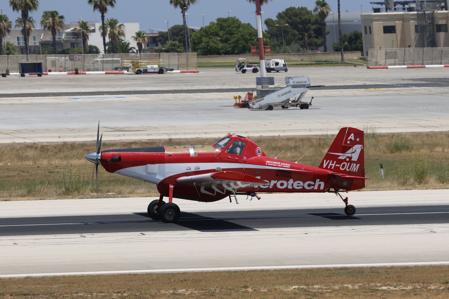 a large turboprop unmanned aircraft on a flight line at a desert test facility, with ground crew equipment visible nearby