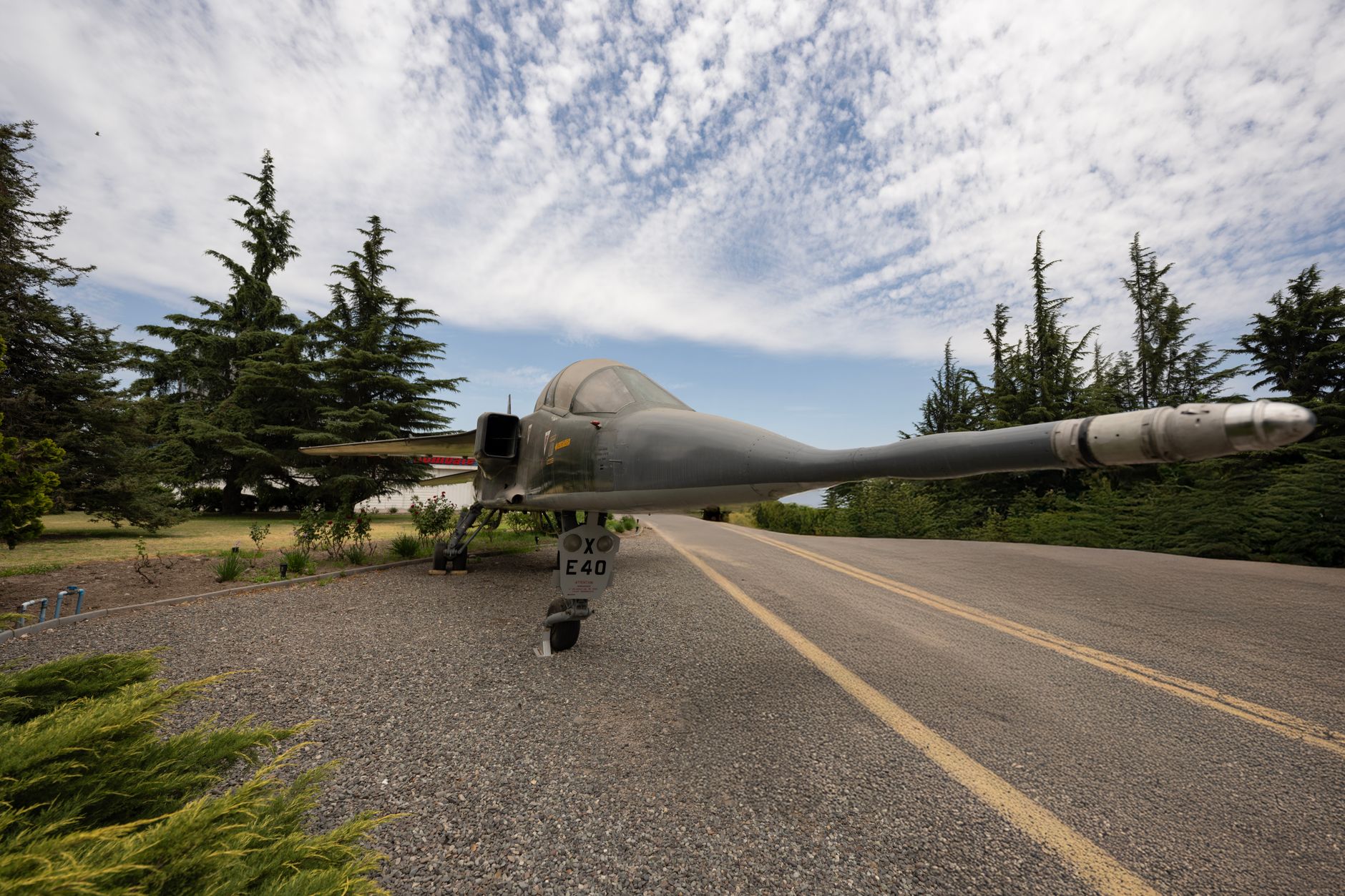 a retired SR-71 Blackbird aircraft on outdoor static display at an air and space museum, viewed from the side at low angle, tarmac surroundings visible