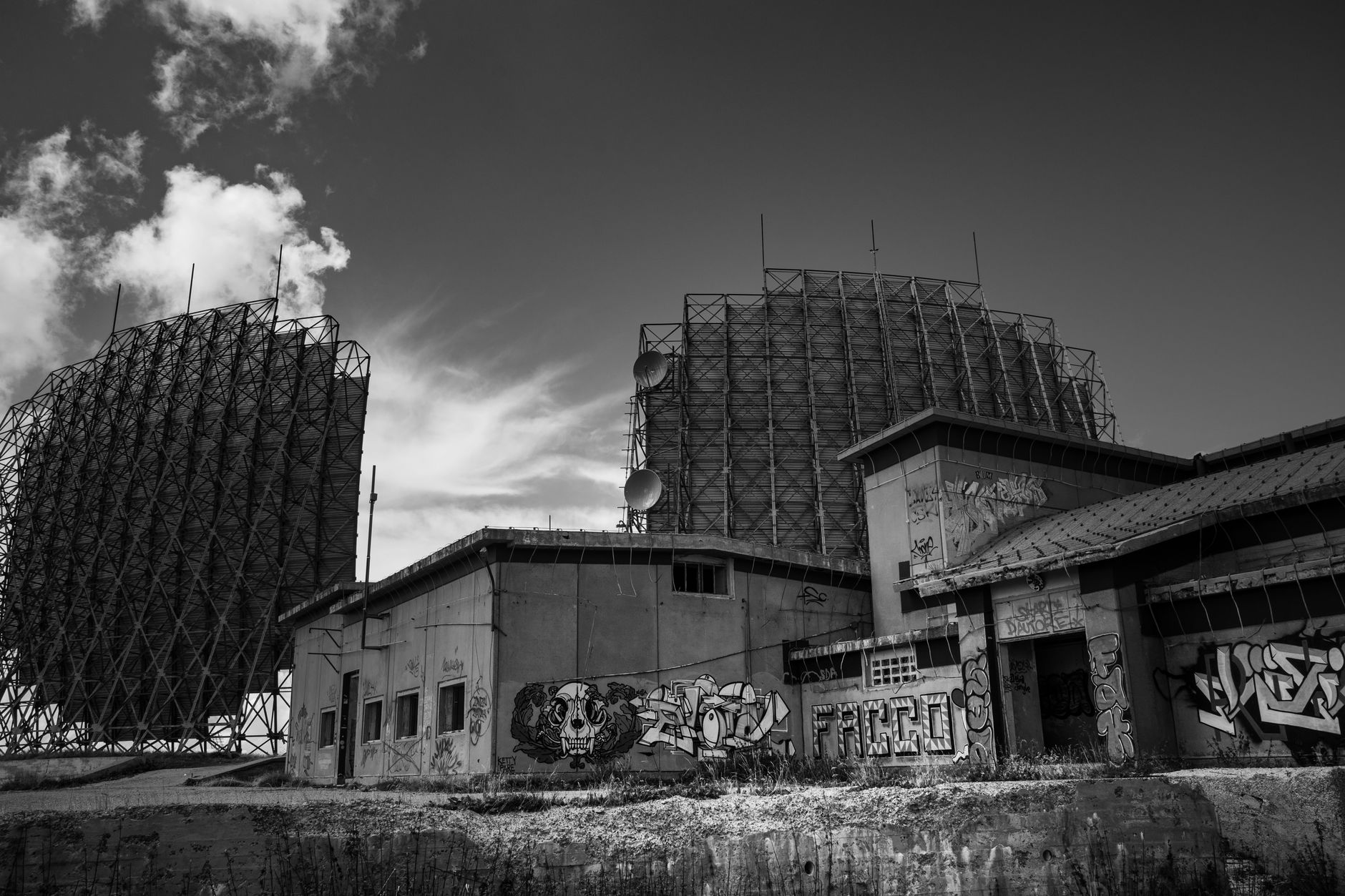 rows of radar antenna arrays and tracking equipment at a mid-century air-defense installation, surrounded by earthen revetments
