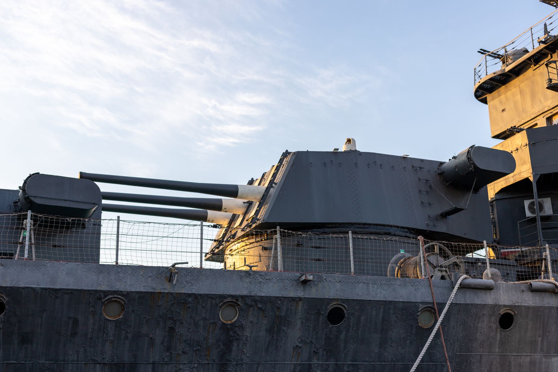 a stationary robotic gun turret mounted on a concrete fortification base in an open field, with sensor housings and a short-barrel autocannon visible, no personnel in immediate foreground